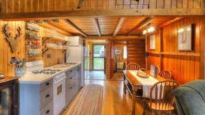 A wooden cabin interior with a kitchen, dining area, and a fireplace. - 10 Haines Landing - We love this classic cabin! Pet friendly and gorgeous views!! (Oquossoc)