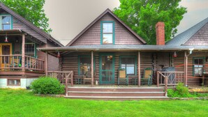 A log cabin with a porch, wooden steps, and outdoor furniture. - 10 Haines Landing - We love this classic cabin! Pet friendly and gorgeous views!! (Oquossoc)