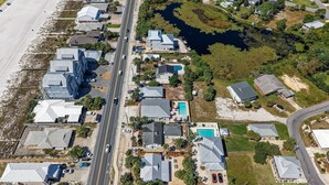 An aerial view of a coastal residential area with houses, a road, and a beach. - Private Pool | Steps To Beach | Fenced Backyard | FLPCB74 (Panama City Beach)