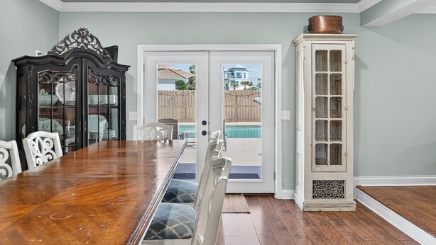 A dining area with a wooden table and chairs, a dark wooden cabinet, and a white cabinet with glass doors. - Private Pool | Steps To Beach | Fenced Backyard | FLPCB74 (Panama City Beach)