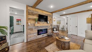Una sala de estar moderna con una pared de madera, una chimenea y un televisor.
