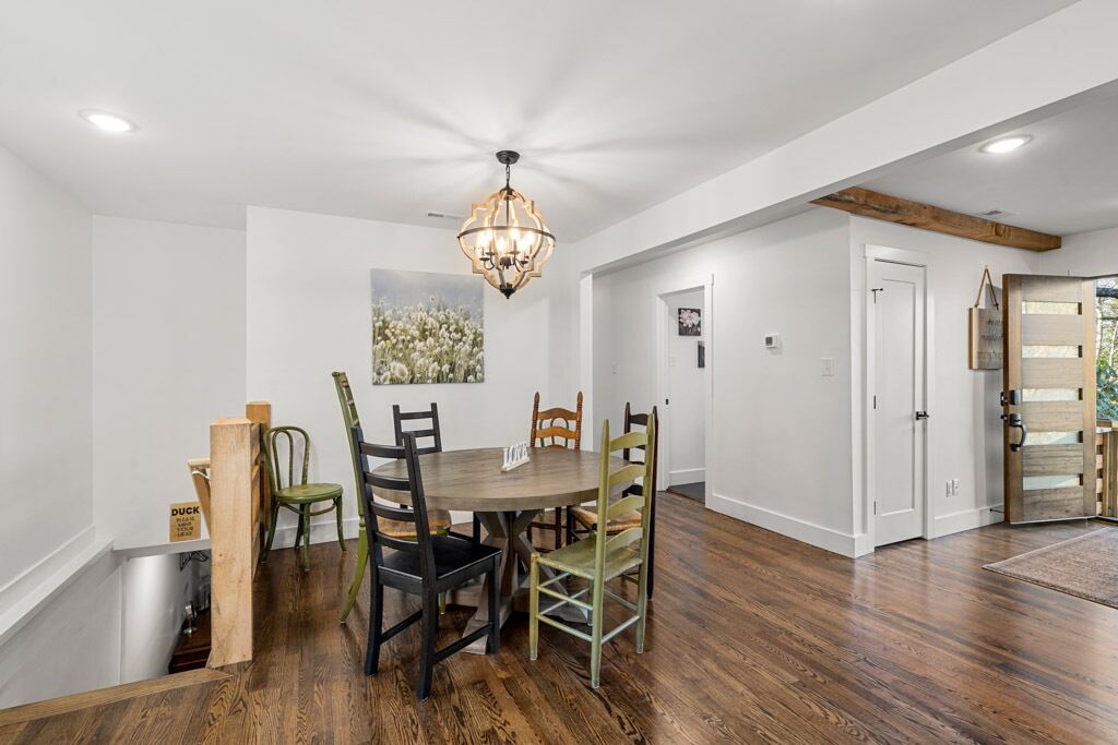 A dining area with a wooden table and chairs, a chandelier, and a painting on the wall.