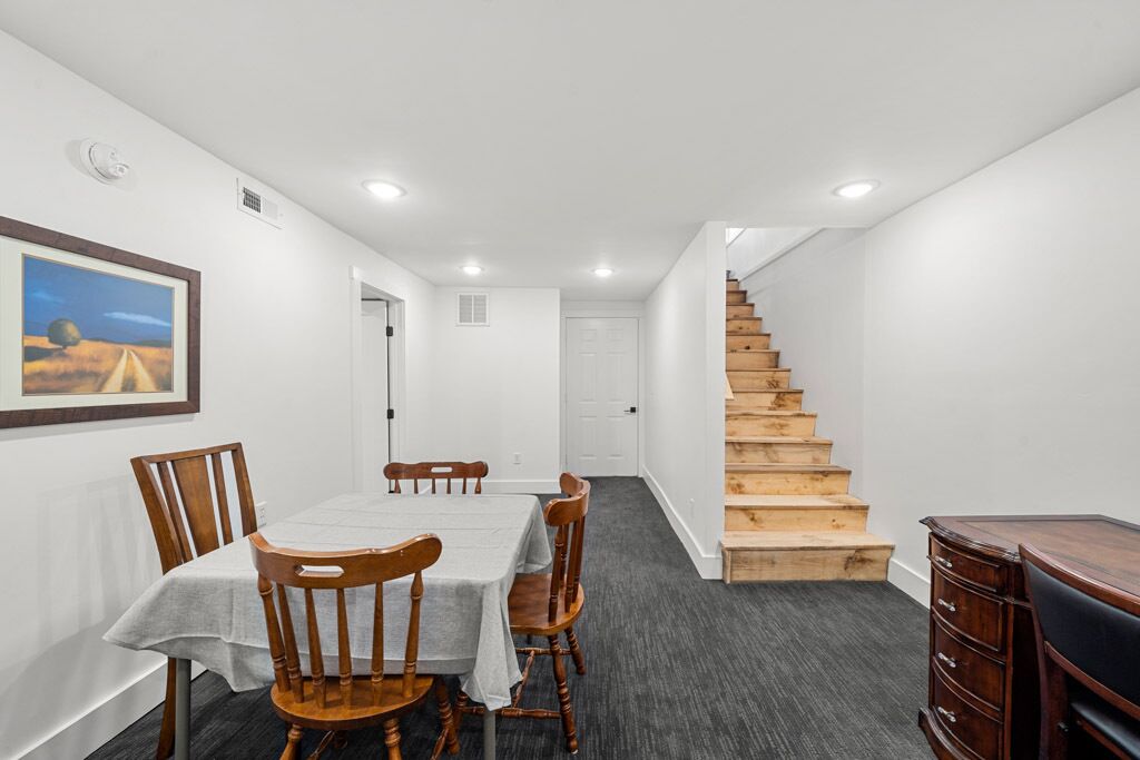 Ein Essbereich mit Tisch und Stühlen, eine Treppe und eine Holzkommode.