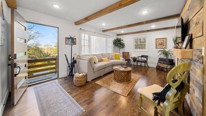 Un salón espacioso con techo de madera, un sofá color beige, una mesa de centro y una silla de madera.