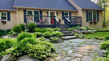 A house with a stone pathway leading to a front porch with a black railing and steps.