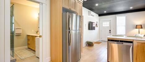 A modern kitchen with a stainless steel refrigerator, wooden cabinets, and a dishwasher.
