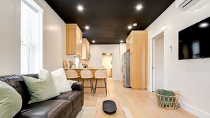 A modern living room with a leather sofa, a coffee table, and a dining area with wicker chairs.