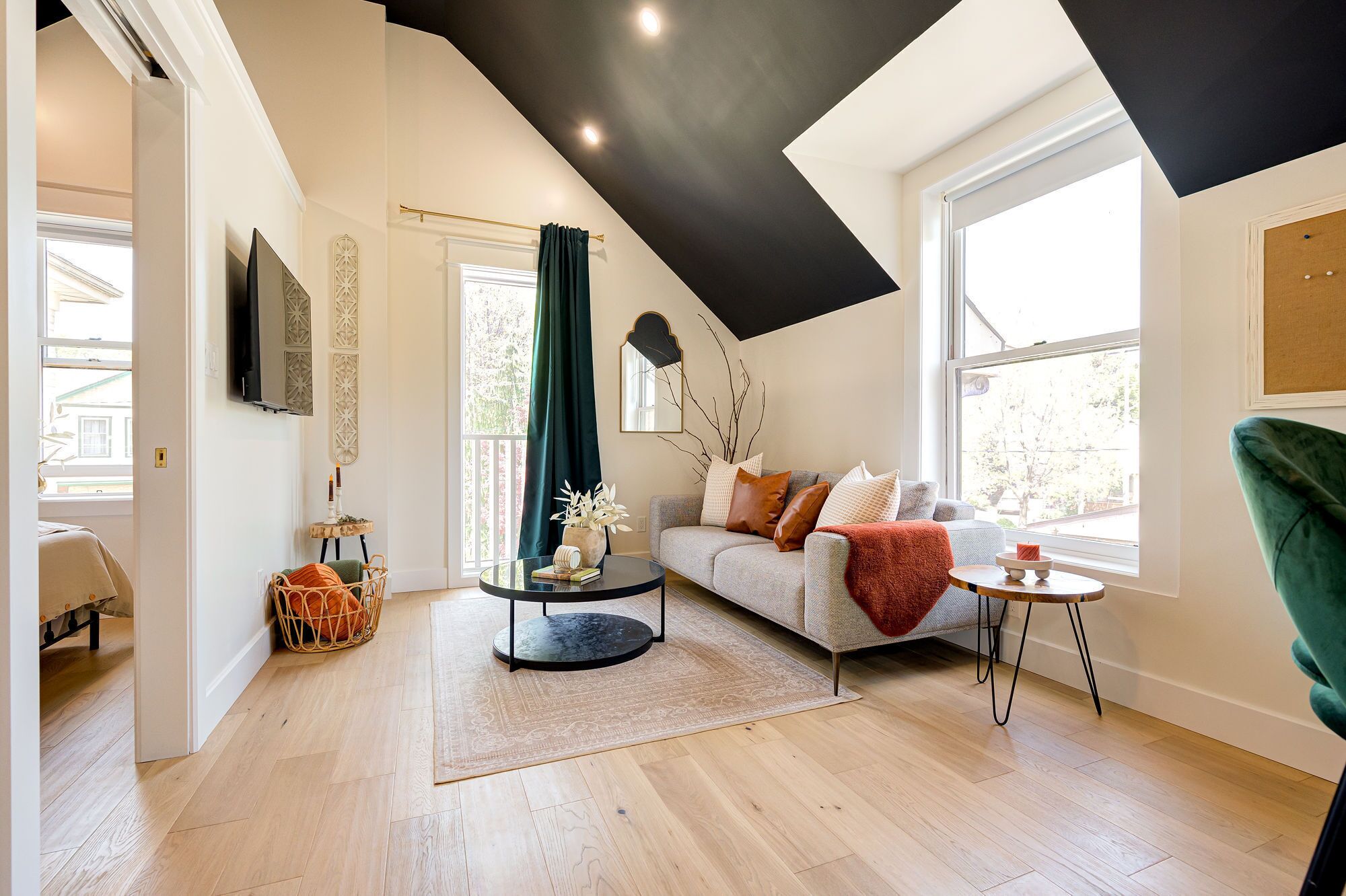 A modern living room with a high ceiling, a grey sofa, a green armchair, and a round coffee table.