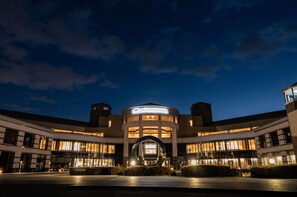 Un hotel moderno con un atrium circular central, varios pisos y una fachada bien iluminada.