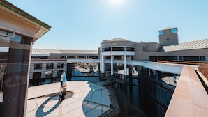 A modern hotel with a central atrium, glass railings, and a clear sky. - Chateraise Hotel Nirasaki Forest (Nirasaki)