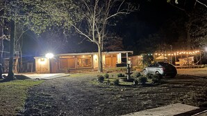 Ein gut beleuchtetes Gebäude mit Garage, einem parkenden Auto und einem kleinen Garten mit Brunnen.