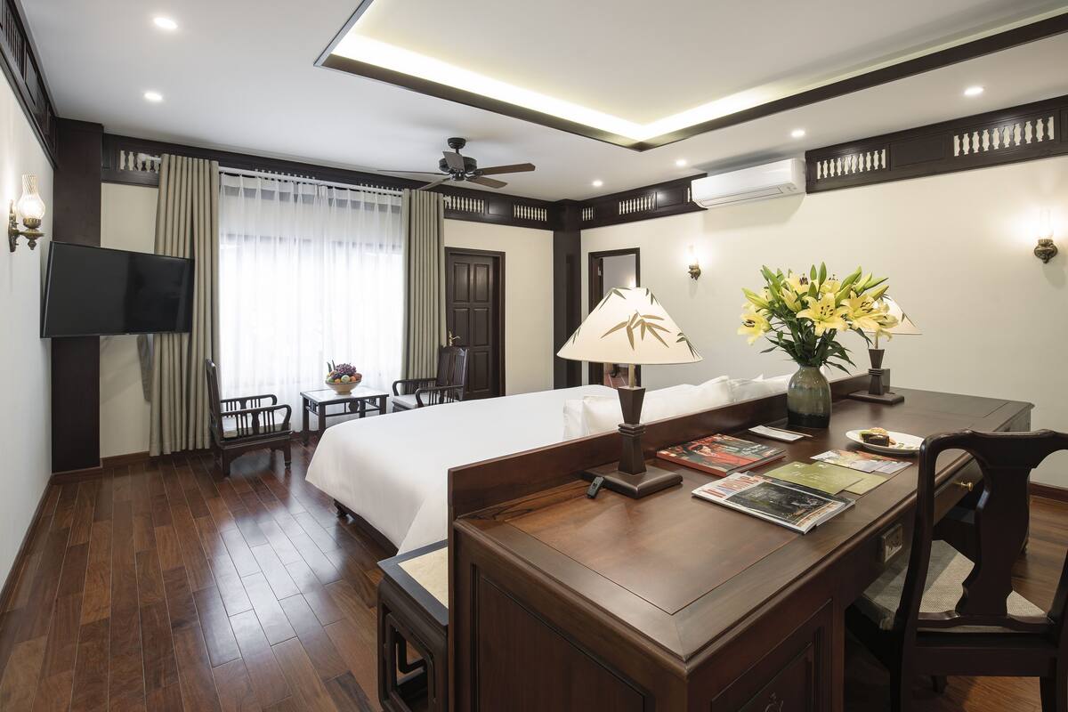 A hotel room with a bed, desk, chair, TV, and a window with curtains.