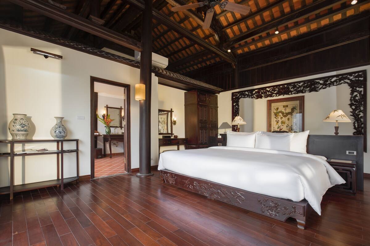 A spacious bedroom with a large bed, wooden flooring, and a ceiling fan.