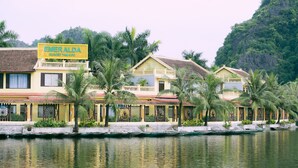 A resort with a signboard, waterfront, and tropical vegetation. - Emeralda Resort Tam Coc (Nam Hoa Lu)