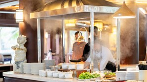 A buffet setup with multiple serving stations, bowls, plates, and a decorative ceramic piece. - Emeralda Resort Tam Coc (Nam Hoa Lu)