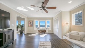 Un salón amplio con ventilador de techo, mesa de billar y un ventanal con vistas al exterior.