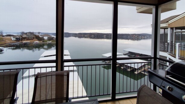 Ein Balkon mit Seeblick, einem Grill und einer Essbereich mit Stühlen und Tischen.