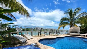 A swimming pool with lounge chairs and a covered fire pit area.