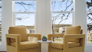 A room with two yellow armchairs facing each other, a small round table with a plant, and large windows offering a view of trees and buildings. - Beautiful condo in Branson (Branson)