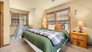 Une chambre à coucher avec un lit, deux tables de chevet, un fauteuil suspendu et un ventilateur de plafond.