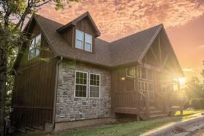 A two-story stone building with a wooden exterior, a stone foundation, and a large front porch. - 4 King Suites | Near Silver Dollar City (Branson West)