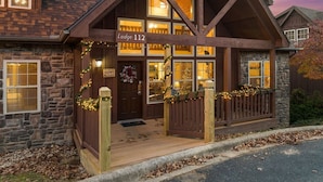 A lodge with a stone facade, wooden beams, and a porch with string lights. - 4 King Suites | Near Silver Dollar City (Branson West)