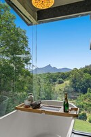 A room with a large window offering a view of a lush landscape and mountains.