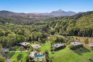 A residential area with multiple houses, a swimming pool, and a lush green landscape with mountains in the background. - La Rocher Eco Retreat (Smiths Creek)