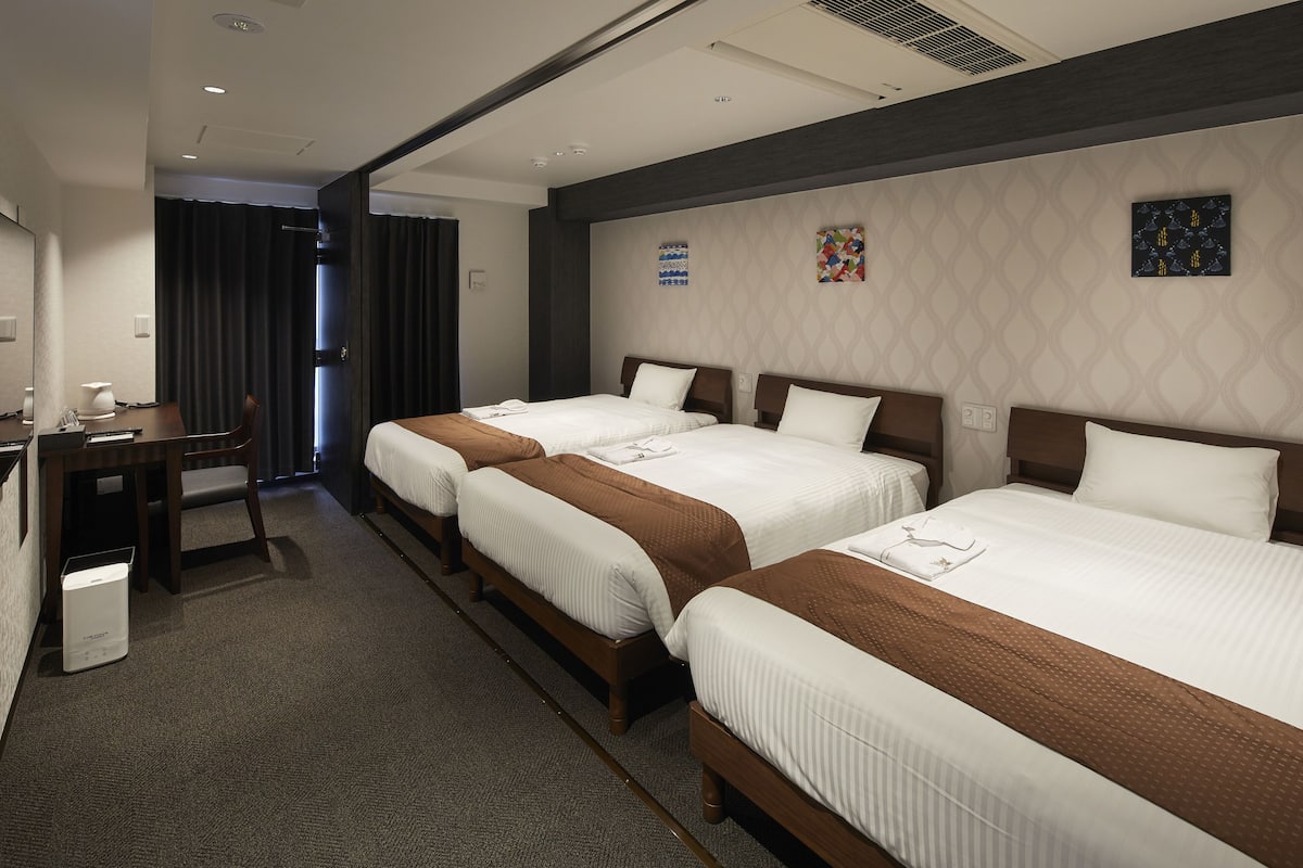 A hotel room with two beds, a desk, and a chair.