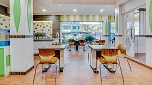 Un restaurante moderno con zona de comedor central, techo alto y amplios ventanales que ofrecen vistas a la calle.