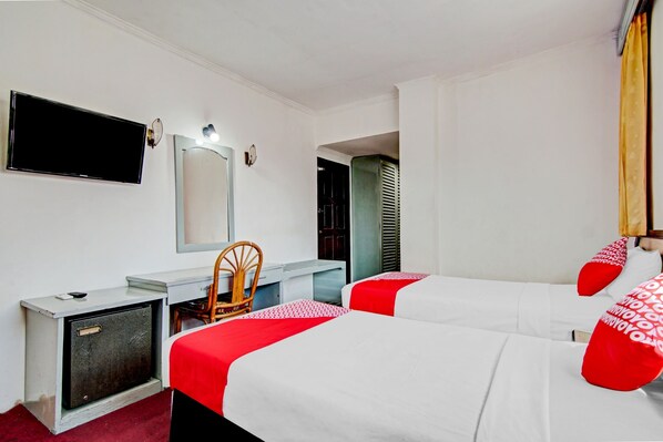 Habitación de hotel con dos camas, un escritorio, una silla, un televisor y un armario.
