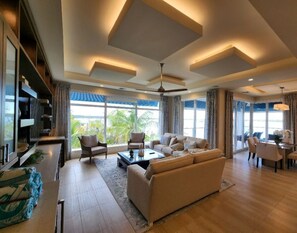 A spacious living room with a large sofa, a coffee table, and a dining area with chairs.