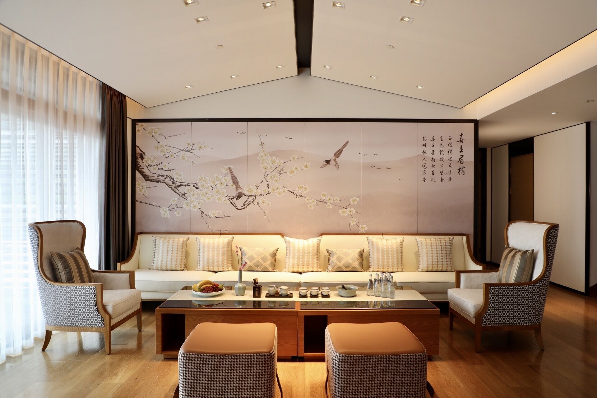 Un salon moderne comprenant un ensemble de canapés, deux fauteuils, une table basse et une grande fresque murale.