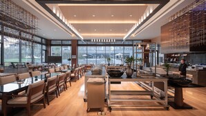 A modern restaurant with a long counter, wooden chairs, and large windows.