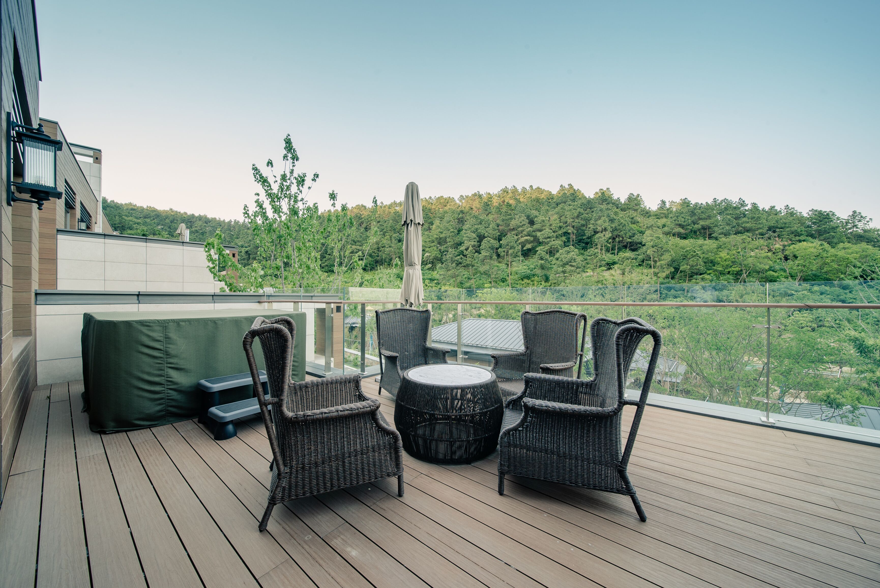 A deck with wicker furniture and a view of a forested area.