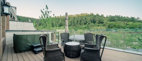 A deck with wicker furniture and a view of a forested area.