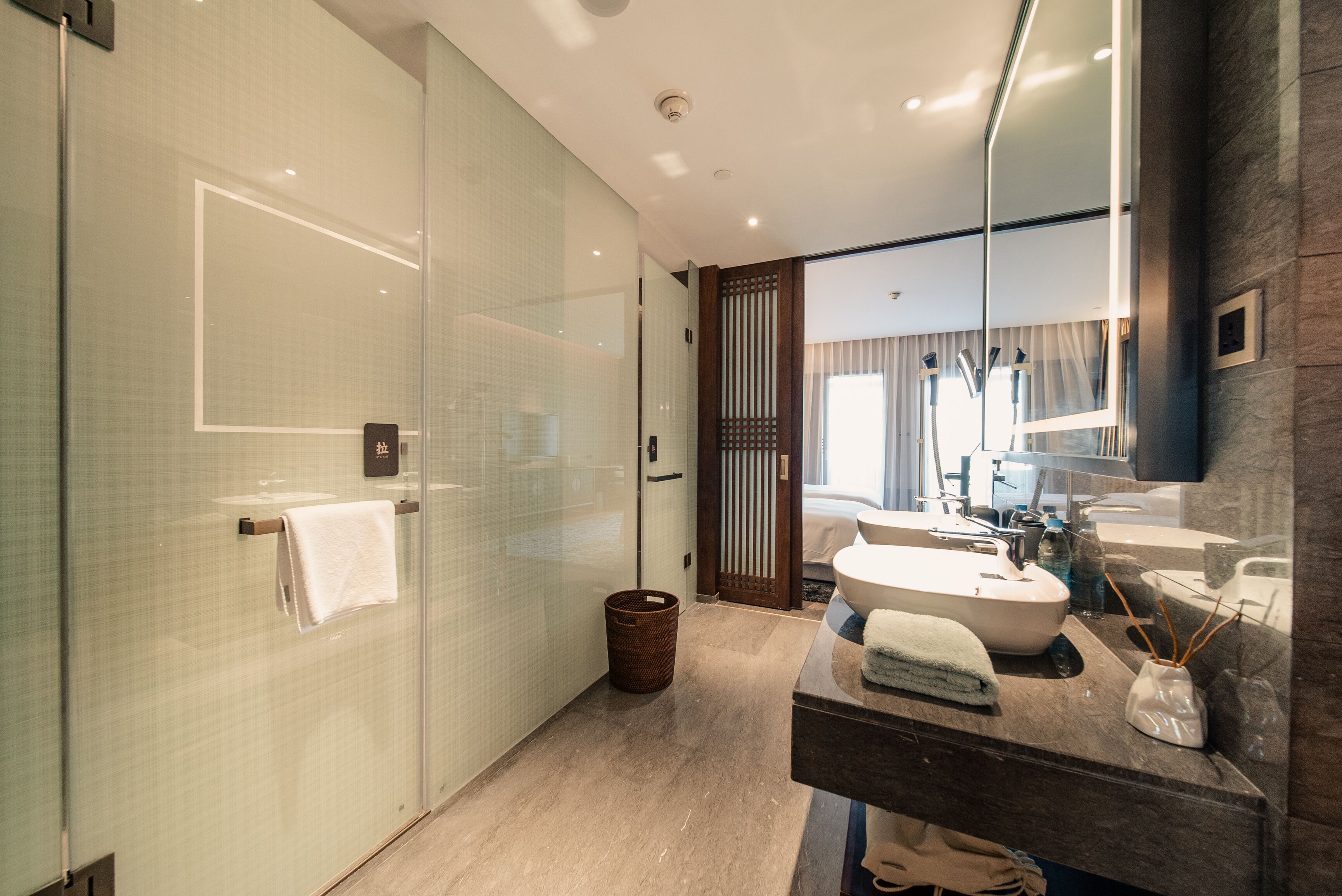 Une salle de bain moderne avec une douche à parois de verre, une porte en bois, un lavabo avec un miroir et un porte-serviettes.