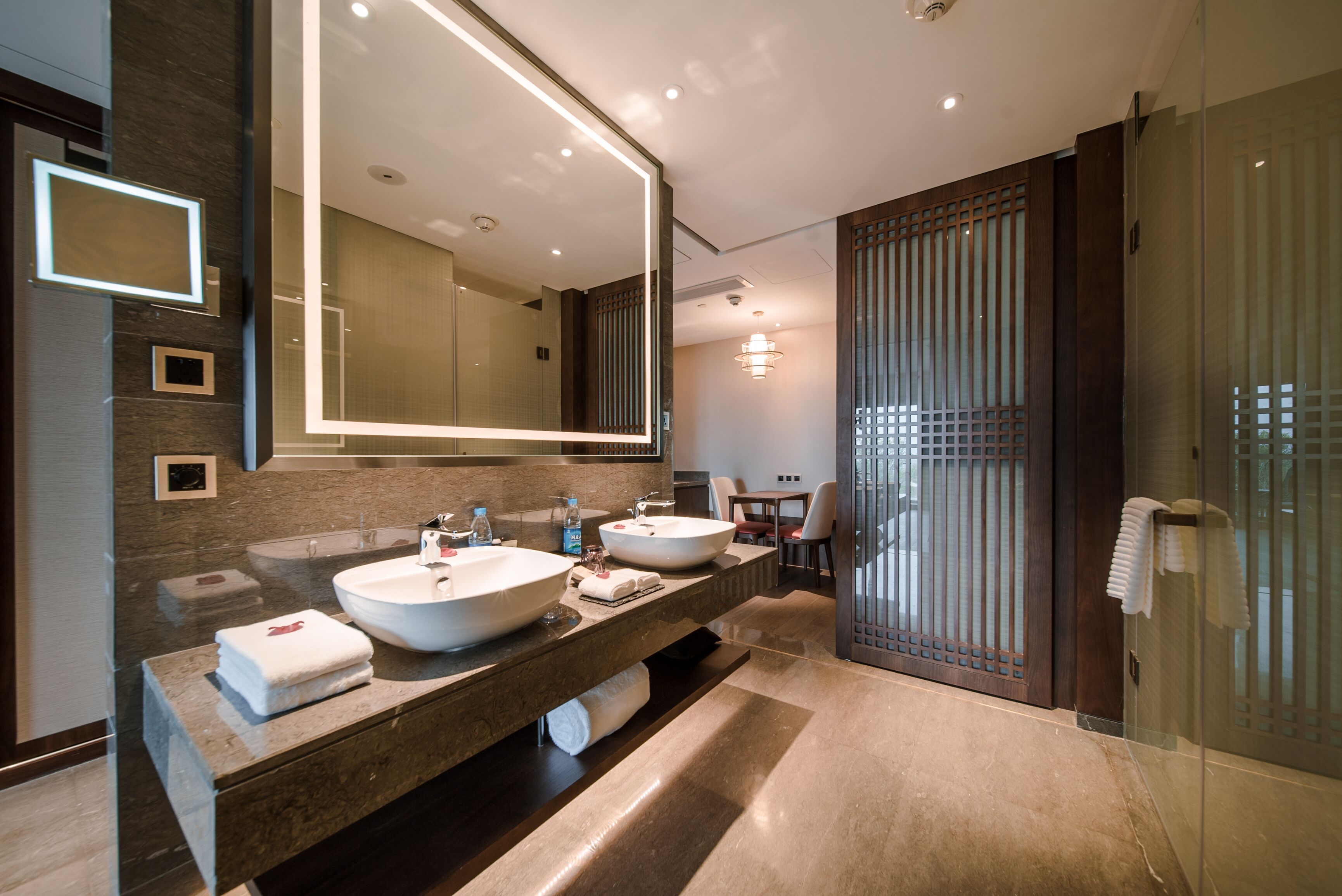 Un baño moderno con dos lavamanos, un espejo grande y una cabina de ducha de vidrio.