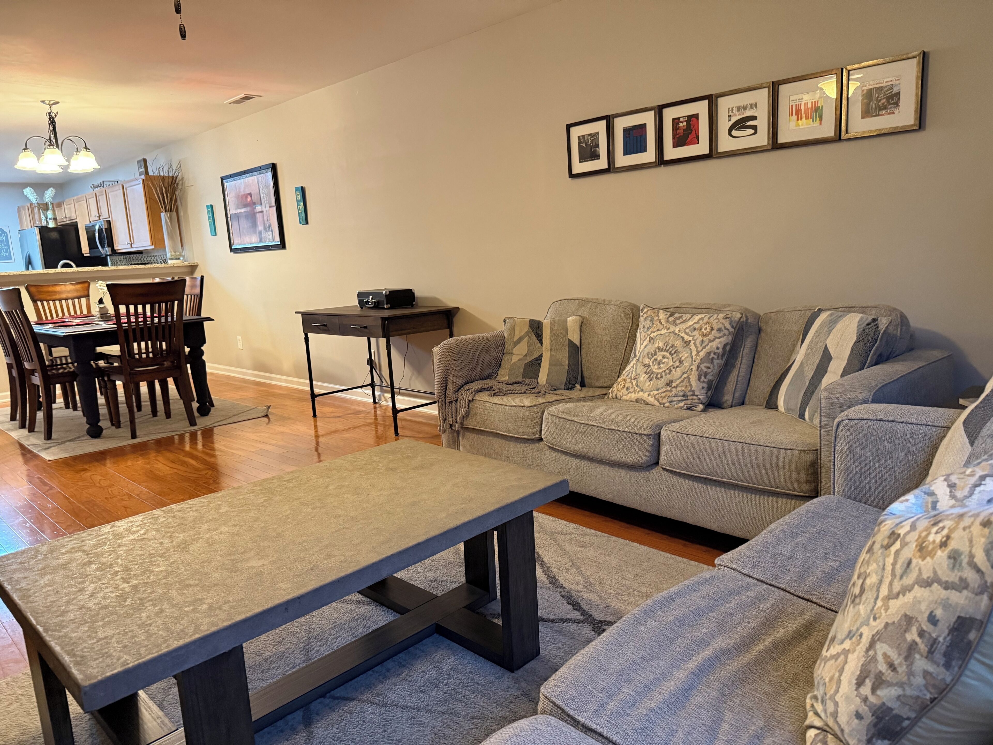 Una sala de estar con un sofá gris, una mesa de centro y un comedor con sillas de madera y una mesa.