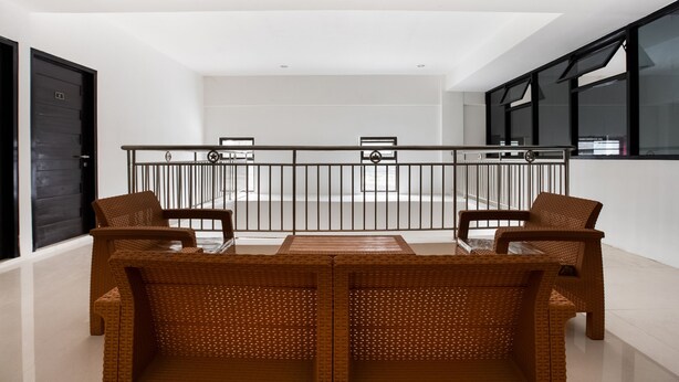 A modern apartment with a balcony, wicker furniture, and a view of the city. - Capital O 3463 Cimahi Guest House (Cimahi)