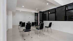 A conference room with a modern design, featuring a white interior, black chairs, and large windows. - Capital O 3463 Cimahi Guest House (Cimahi)