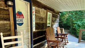 A wooden porch with rocking chairs and a door with a 'Home Sweet Home' sign.