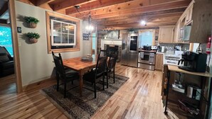 A wooden interior with a dining area, kitchen, and a view of the outside.
