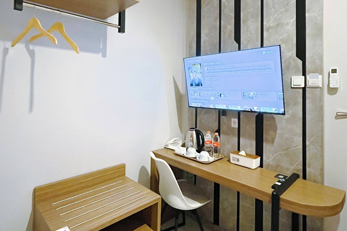 A modern hotel room with a desk, chair, and a television mounted on the wall.