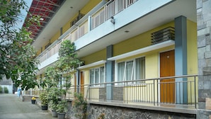 A multi-story hotel with balconies, potted plants, and a stone facade. - Front One Resort Indraloka Temanggung (Temanggung)