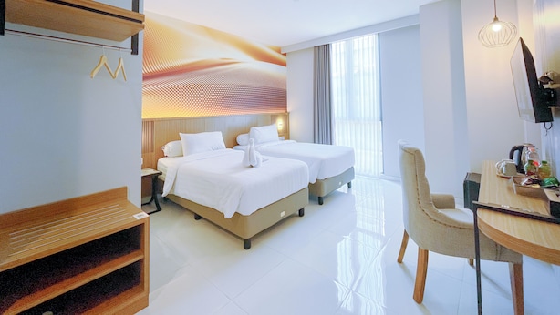 A hotel room with two beds, a desk with a chair, a TV, and a large window with curtains. - Front One Resort Indraloka Temanggung (Temanggung)
