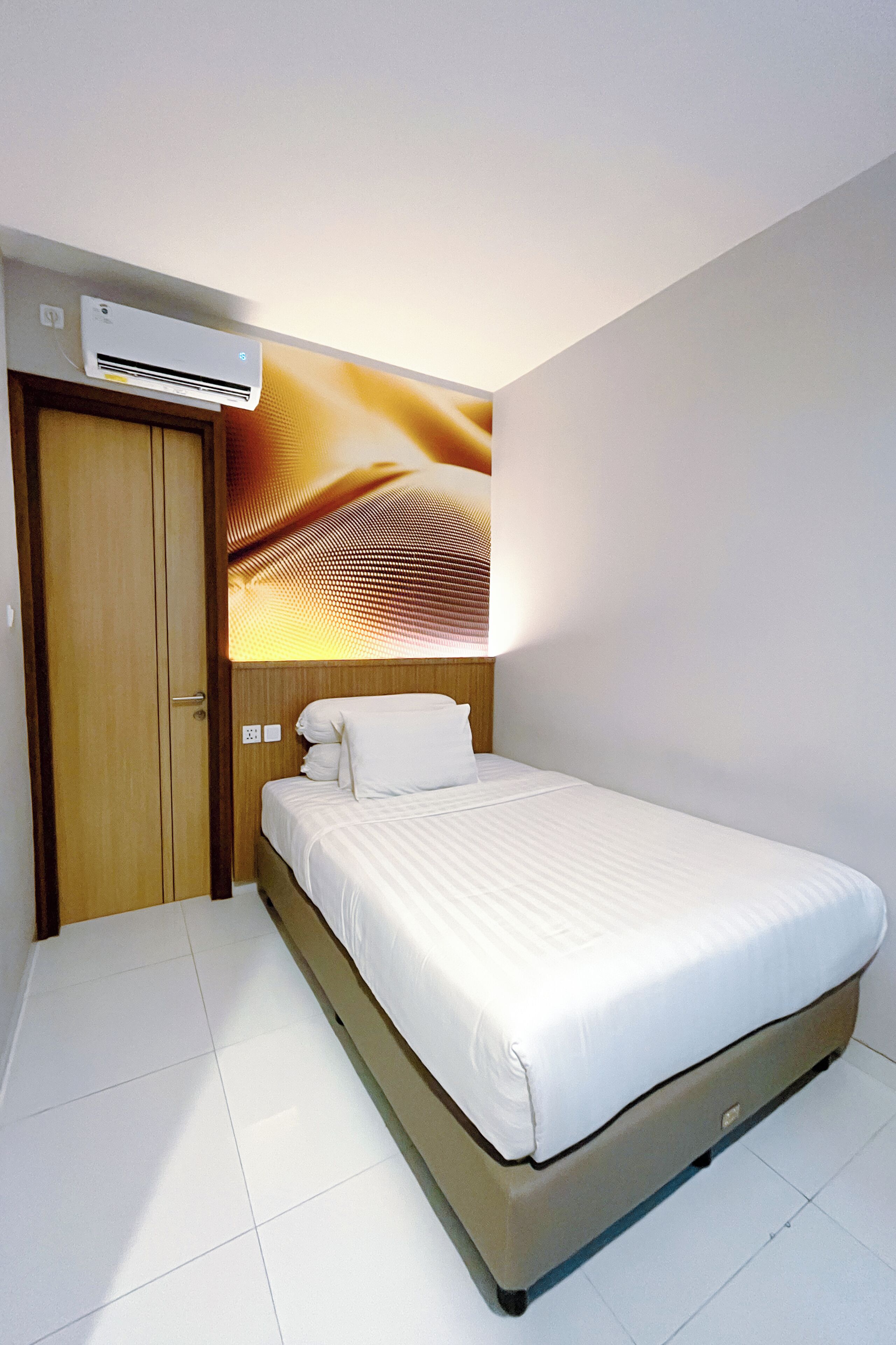 Una habitación de hotel con cama, armario de madera y unidad de aire acondicionado.