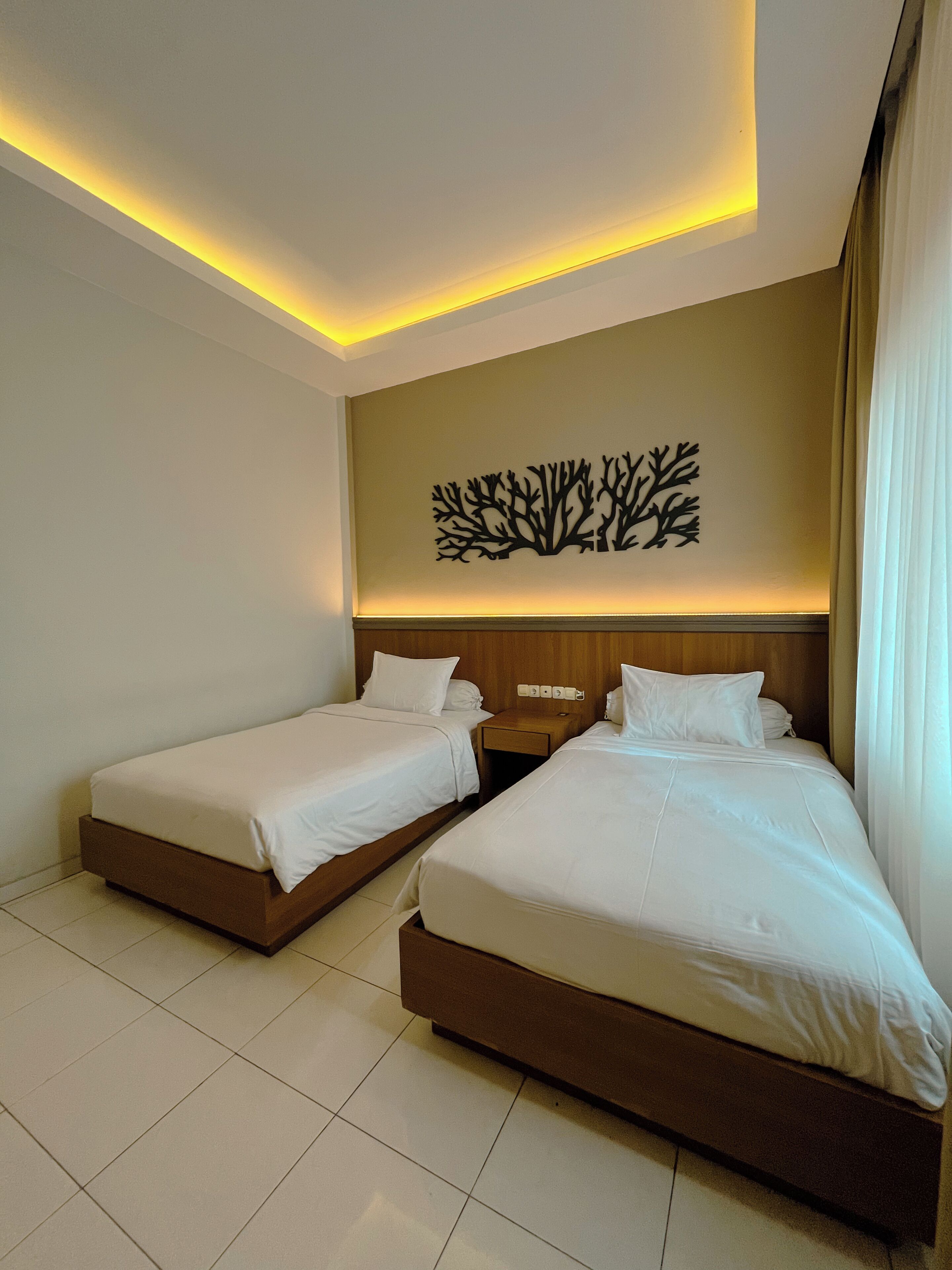Een hotelkamer met twee bedden, een kunstwerk aan de muur en een nachtkastje.