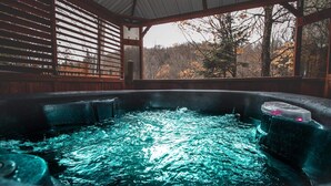 A hot tub with a view of trees and a wooden structure. - Cozy cottage with hot tub! (Saint-Adolphe-d'Howard)