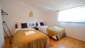 Quarto com duas camas, um candeeiro de tripé e uma janela com cortinas.